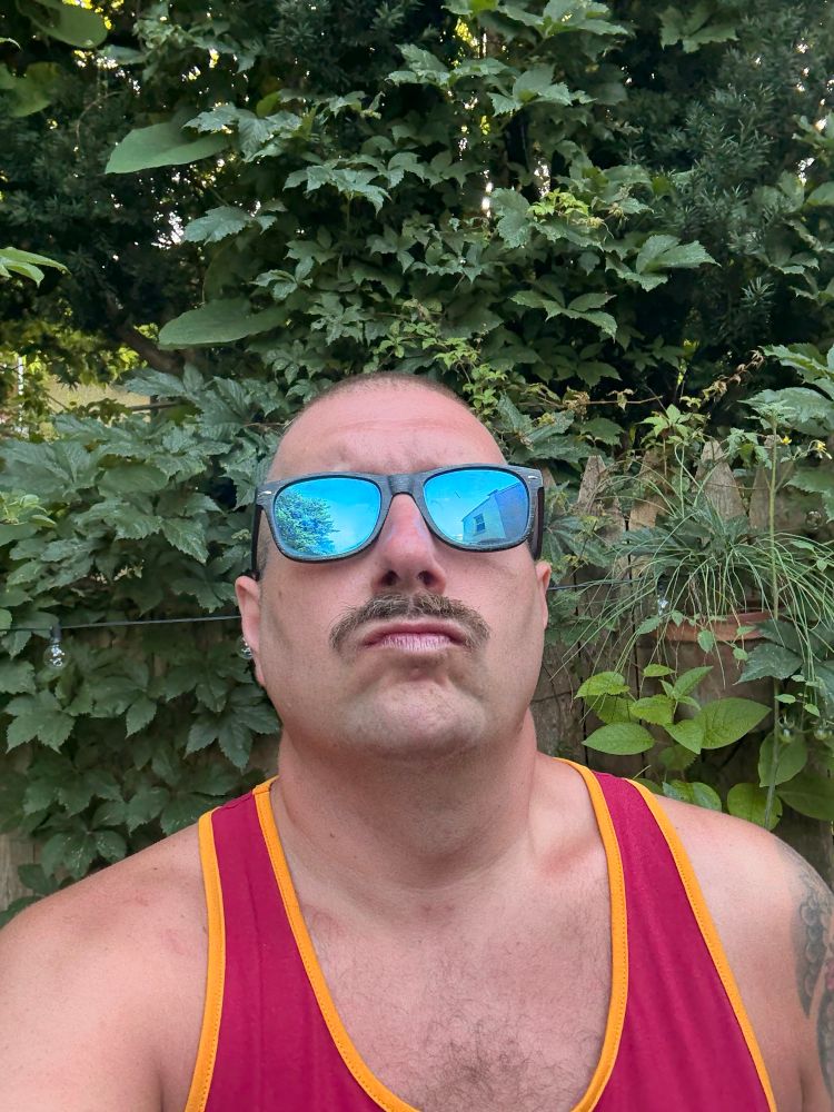 Man in summer in front of plant wall. 