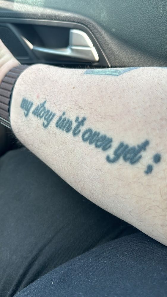 picture of tattoo with a semicolon that says "my story isn't over yet"