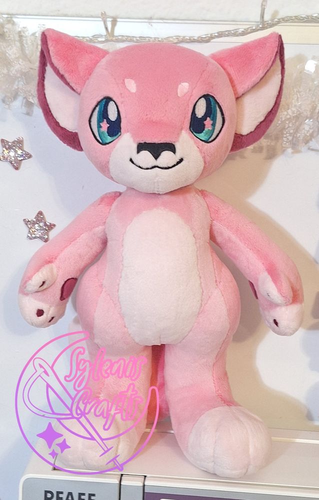 A plush Anthro character in pink fabric with teal eyes