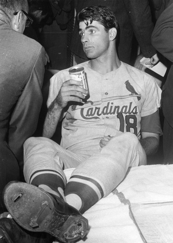 A black and white photo of Cardinals 3B Mike Shannon in the clubhouse with his feet up and a can of beer