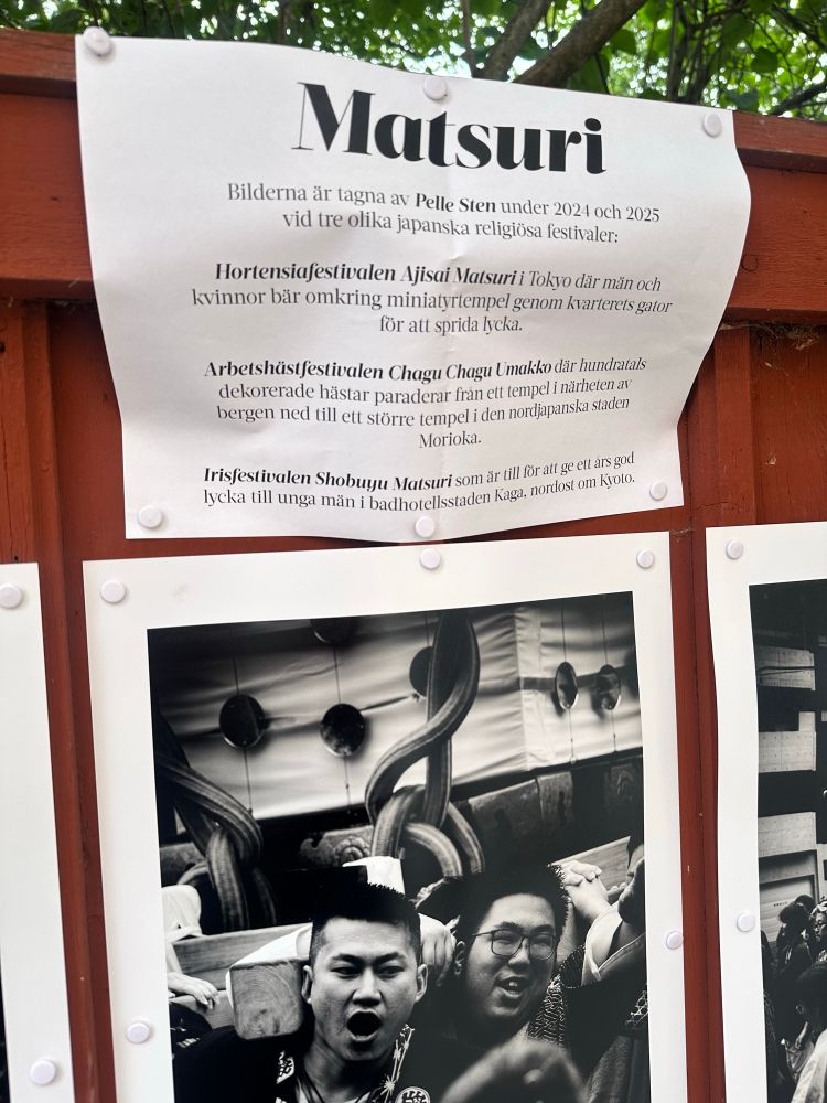 På bilden ser man ett rött plank med en vit pappersutskrift och delar av fotoprintar. På papersutskriften beskrivs projektet och på bilden syns två glada män som bär en tampelminiatyr. 