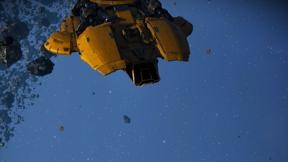 A view of the front of the same yellow spaceship, showing the industrial-styled cockpit, looking a bit like a construction vehicle. The two rounded-wedges to either side of the cockpit can be seen to be slightly above. Just out of frame is the large shallow dome of the top of the ship.