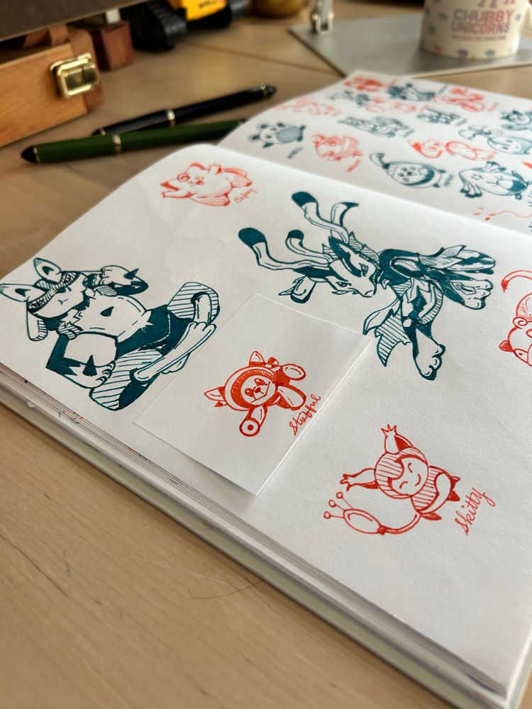 Dark green and orange ink drawings of various Pokemon on a sketchbook spread 
