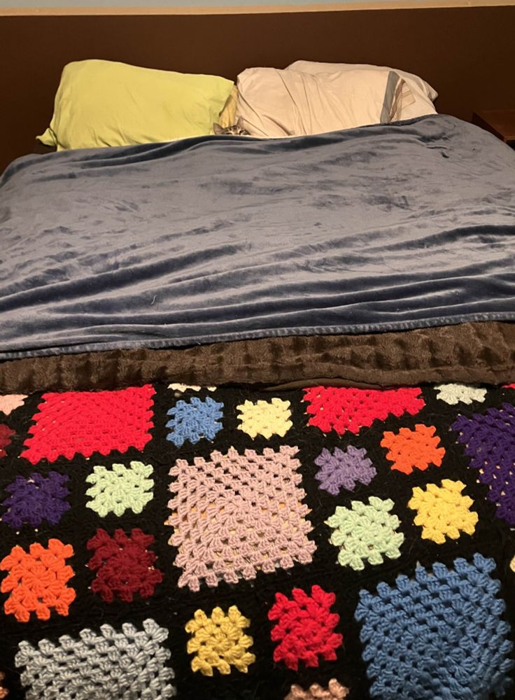a queen size bed with lots of blankets on it, none of which match in pattern or texture
in the middle at the head is a little kitty face