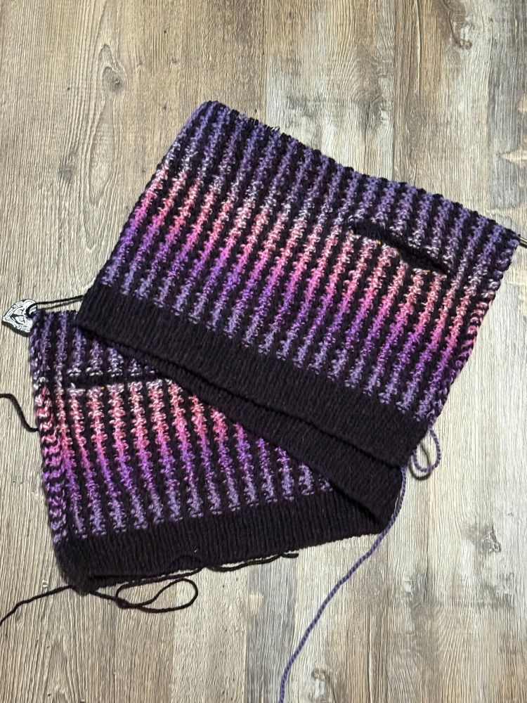 Handknit cardigan in progress from bottom up, in purple pink gradient yarn