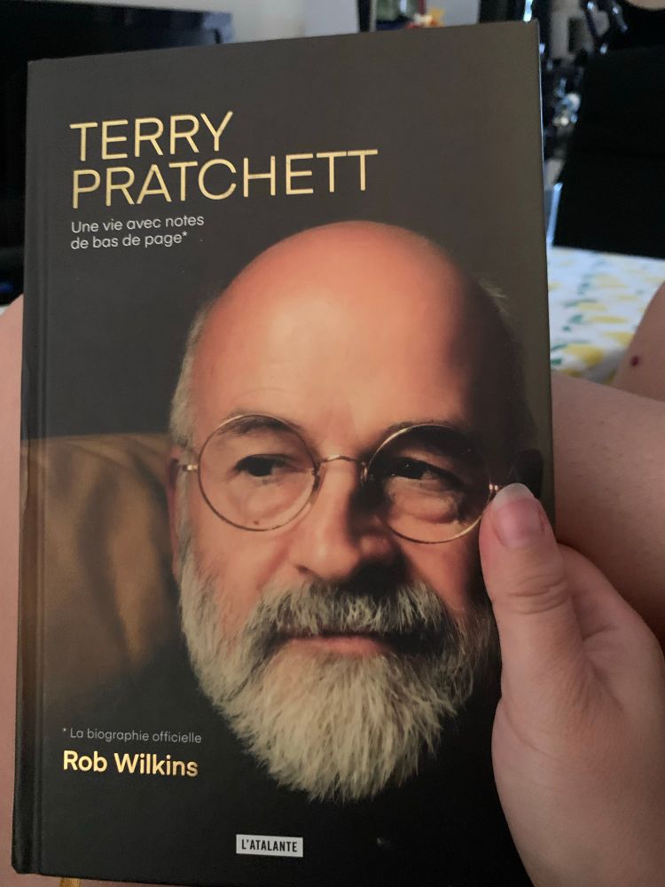 Photo de la couverture de la biographie officielle de Terry Pratchett par Rob Wilkins. On y voit un portrait de l’auteur sur un fond noir. 