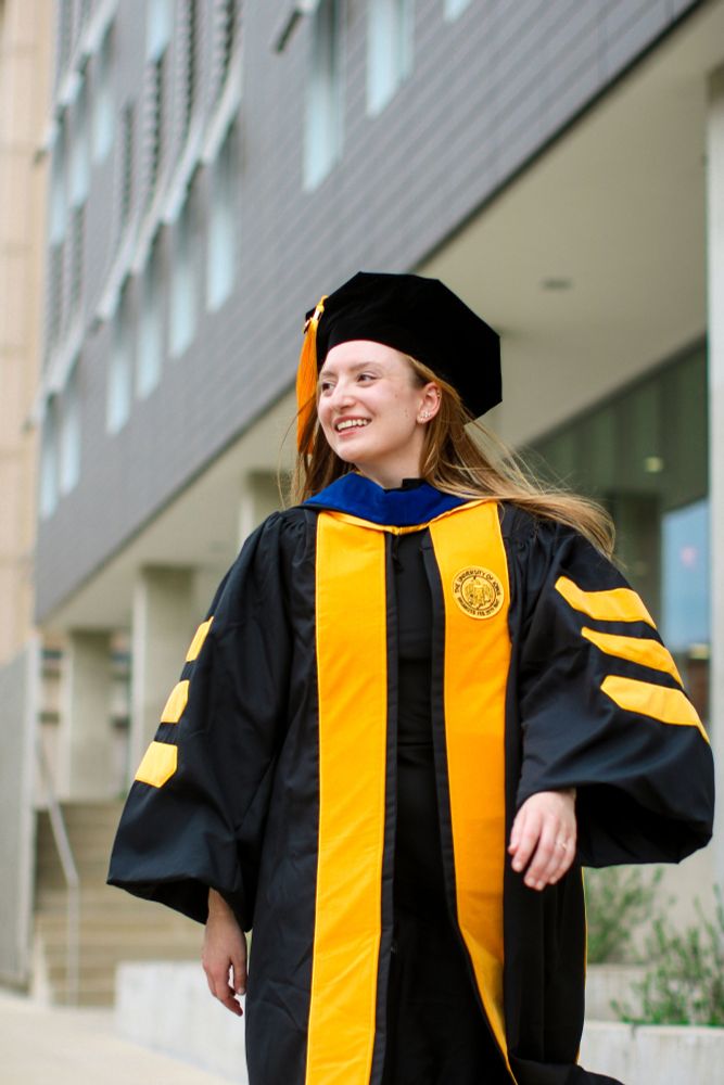 Lilly in graduation regalia, looking off into the distance and smiling
