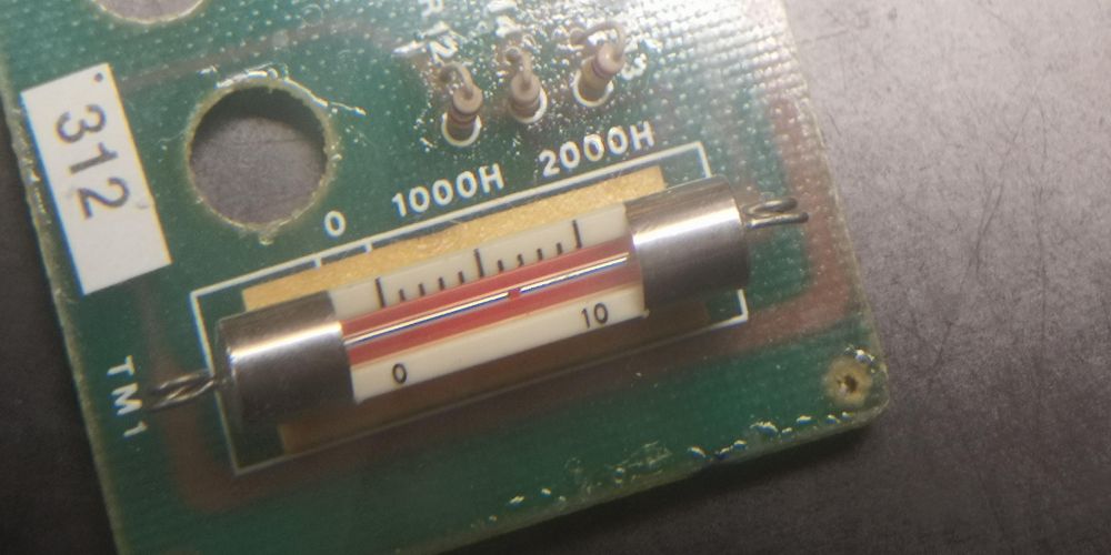 Fuse-like tube on a PCB. Under it is a scale. Silkscreen says 0, 1000H, 2000H. The fuse-object is filled with a thin line of mercury with a dot.