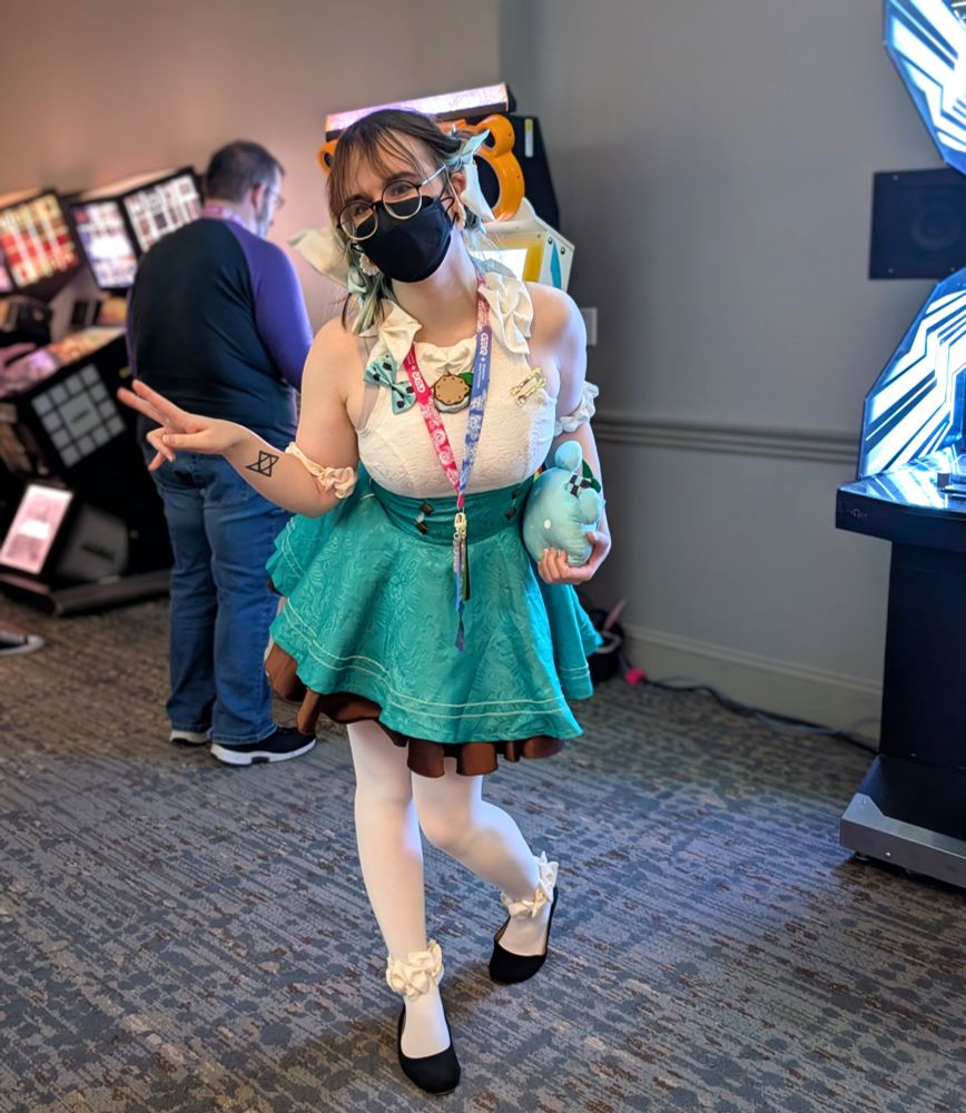 Im standing in the arcade, in a cosplay of a Miku fan art, lit up by the glow of an arcade machine sitting slightly out of frame