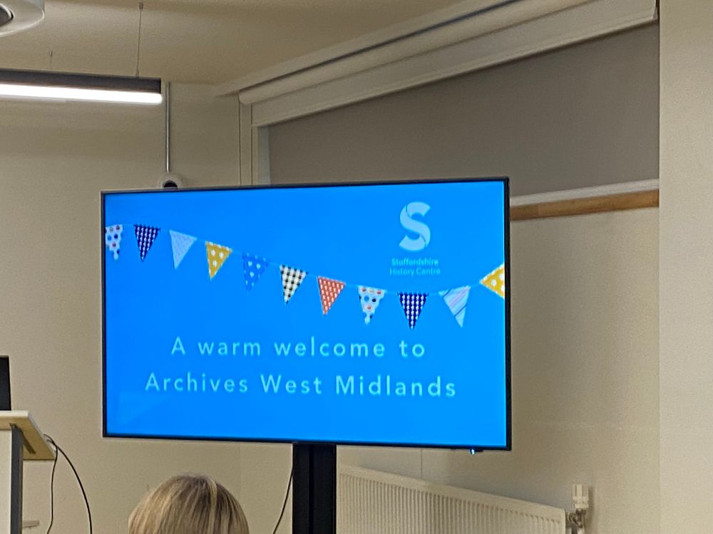A screen with blue background and multi-coloured flags with text A warm welcome to Archives West Midlands