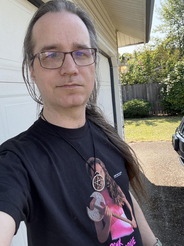 Selfie outside my house in a shirt depicting Isabel from I Saw the TV Glow with my pentagram necklace on. 