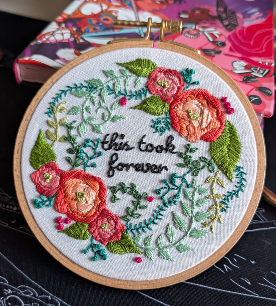 An embroidery hoop with several roses and vines with "this took forever" stitched in the center