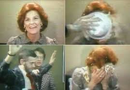 four grainy, desaturated old video stills, first a conservatively styled woman with red hair smiling at the camera, second a hand reaching into the frame to slam a pie in her face, third a man holding his hands up looking grim, fourth the woman again with her head in her hands, full of pie