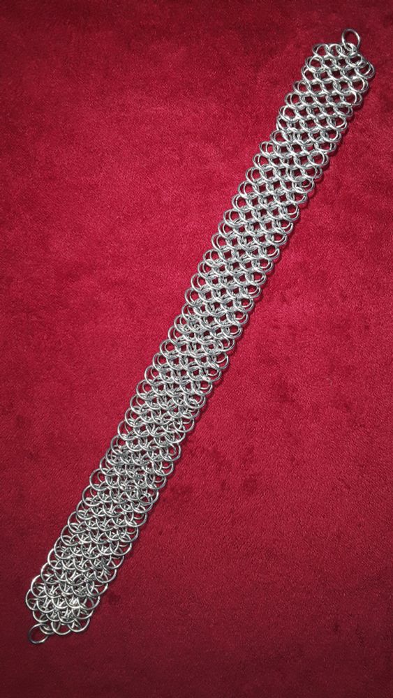 A chainmail choker in Dragonscale weave, on a red velvet background.