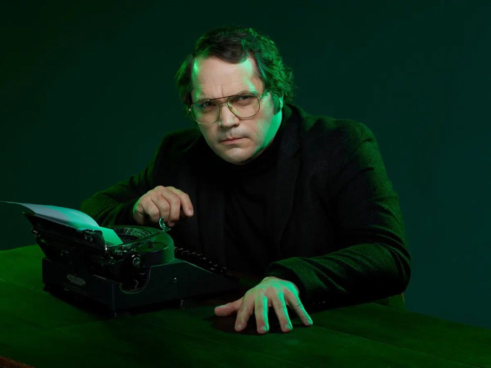 Prolific and iconic horror writer Garth Marenghi in front of a typewriter covered in a green glow. 