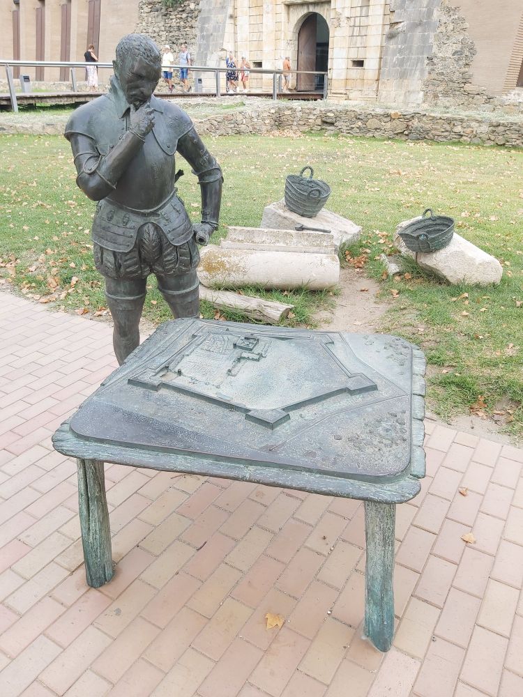 Statue of a man thinking, looking down on a table.