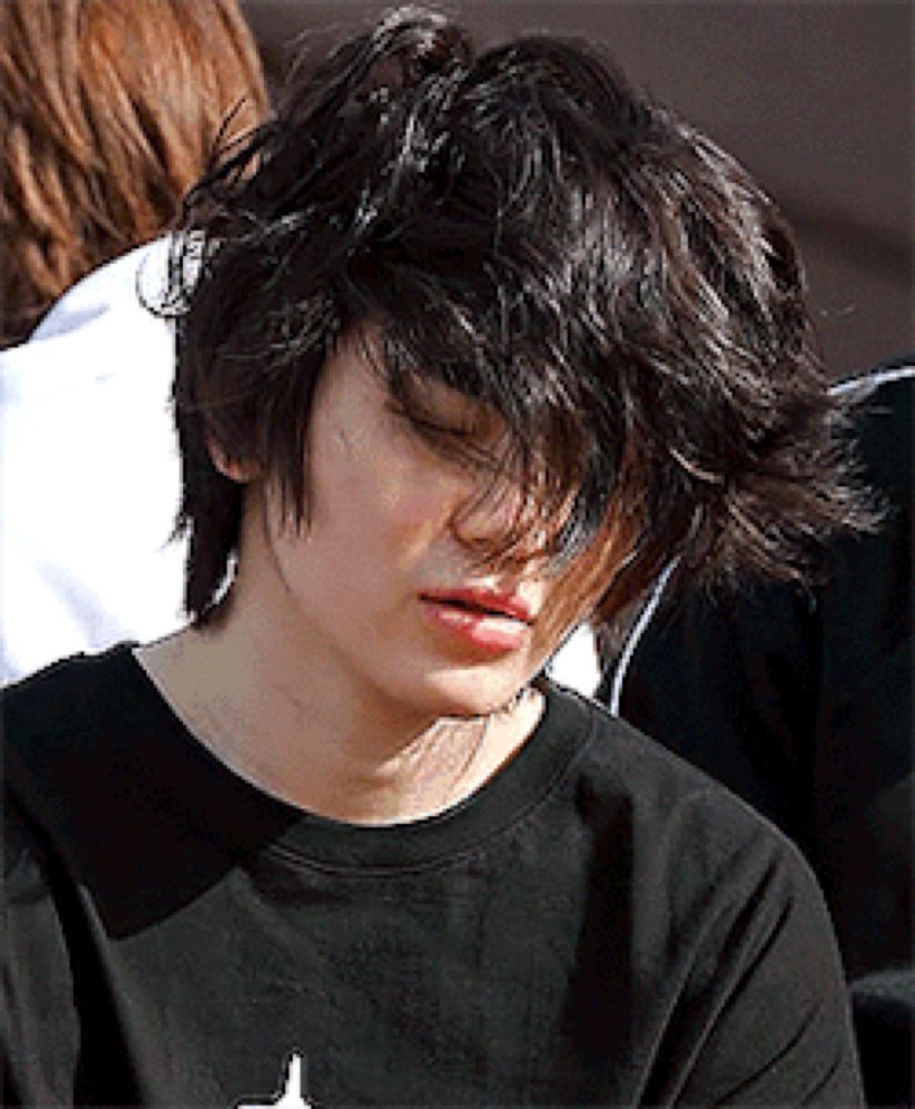 a young man with messy hair is wearing a black shirt