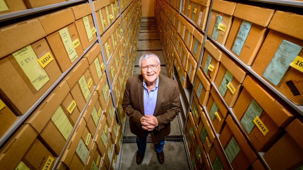 A man stands between two large storage shelves