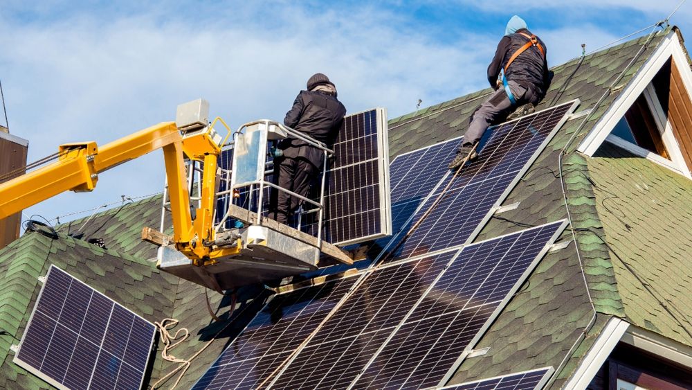 Two men installing solar panels on a roof.