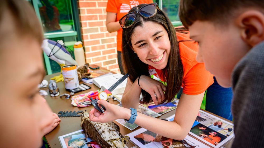 A person smiling at kids at science activity.