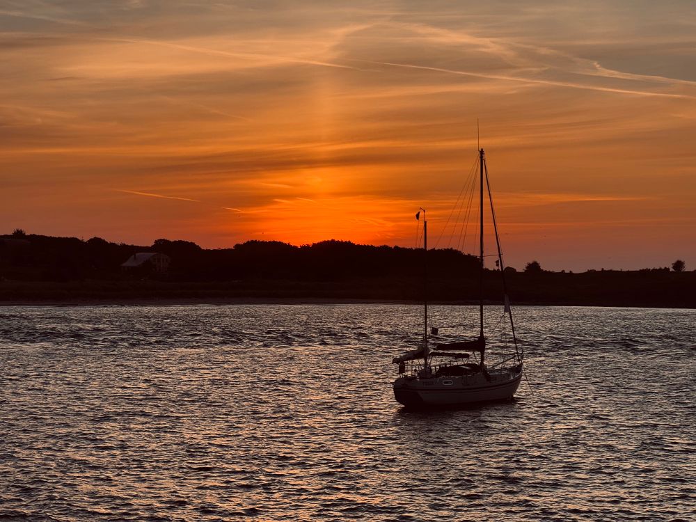 Sun rising up behind Gugh with one lone yacht in Cove 