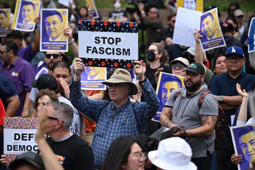 A crowded valley with an attendee holding up a sign that says stop fascism