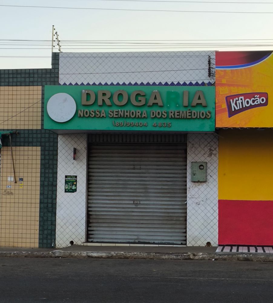 Foto de uma drogaria com letreiro verde, mas no letreiro a letra R está faltando, dando a impressão de "Droga IA"
