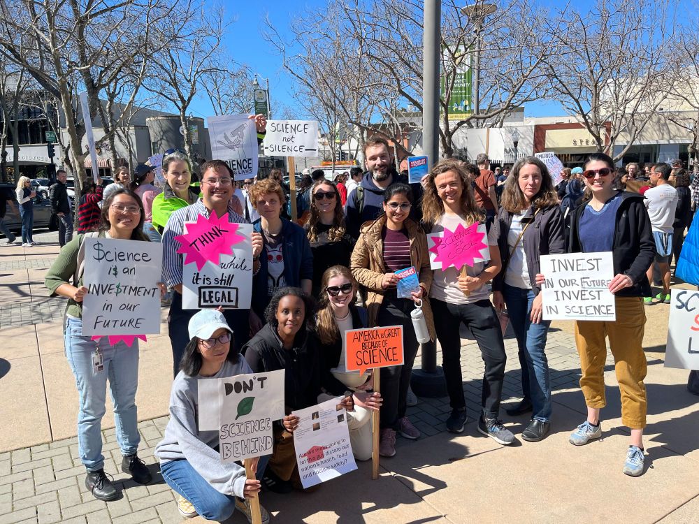 Scientists holding posters with slogans related to saving US science