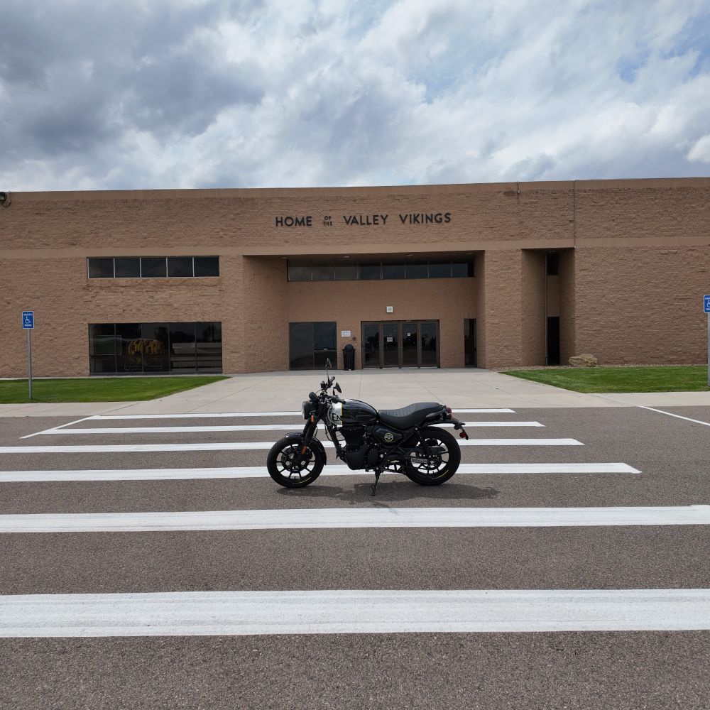 A black and silver Royal Enfield Hunter 350, parked in front of a huge, imposing rural high school. The school is a light brown/taupe, a grey sidewalk framed by two patches of green grass, the Hunter between the white stripes of the crosswalk.



(Thank God it was Sunday because the kids would've razzed me if they saw me almost drop this thing when I parked it.)



Thought I was gonna say CORN, didn't you?
