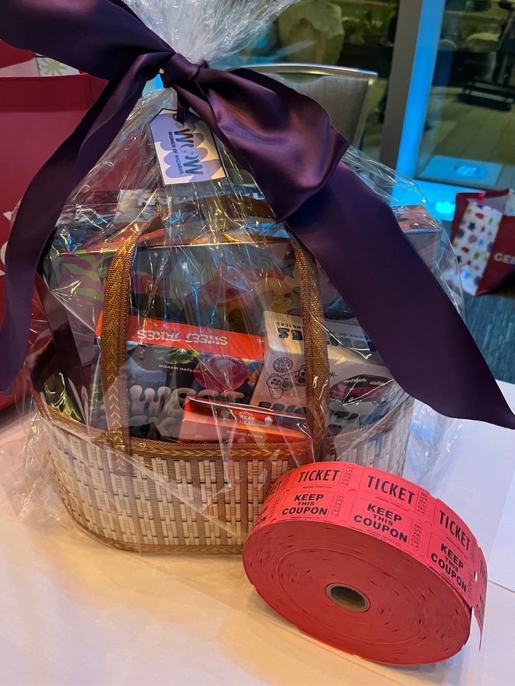 GeekGirlCon gift basket with big purple ribbon sits on a table with a big roll of red raffle tickets.