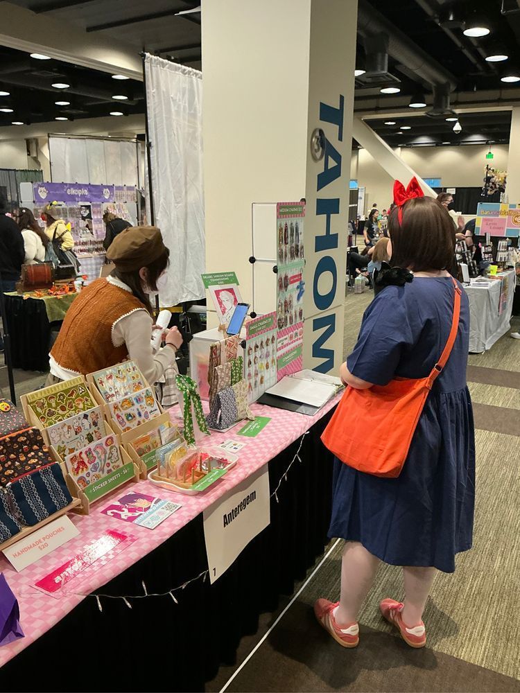 Cosplayer dressed as Kiki from Kiki's Delivery Service shops at the booth of a GeekGirlCon vendor, Anteregem.