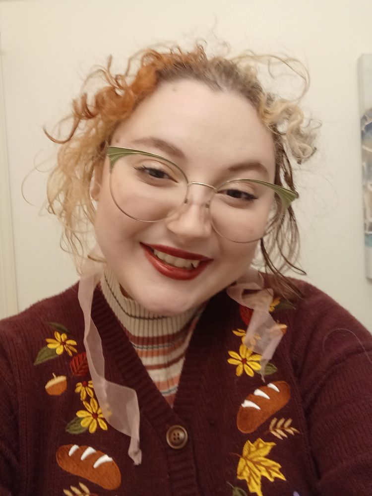 picture of bee wearing a red kikis delivery service cardigan, a bow in their hair, green glasses and red lipstick