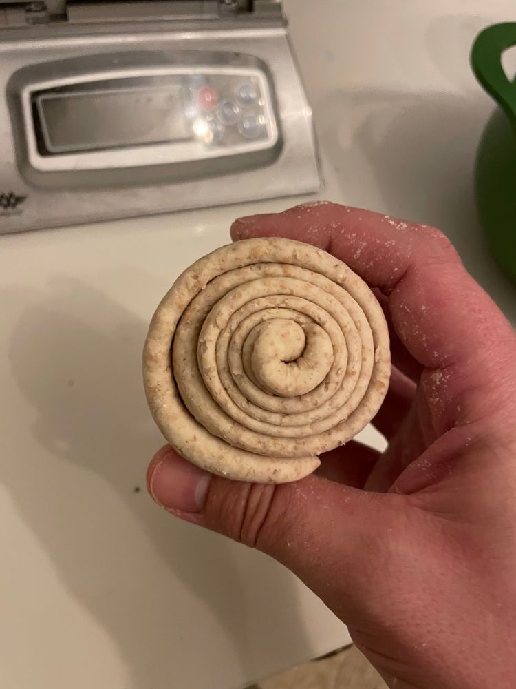 A rolled up ‘stiff’ sourdough starter against a white worktop. There are digital scales in the background.