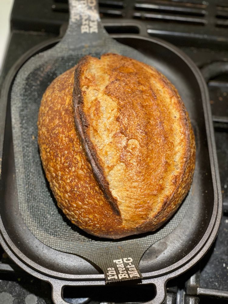 A sourdough batard loaf in a cast iron pan.