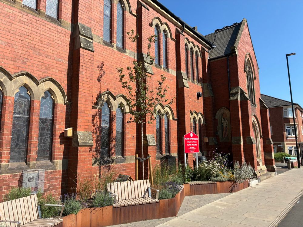 The garden and benches in the foreground, with the church behind and stunning, clear blue skies. 