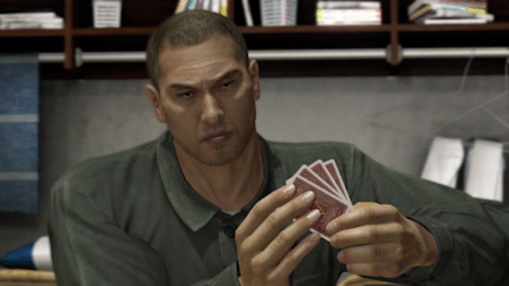 a man in a green shirt is holding four playing cards