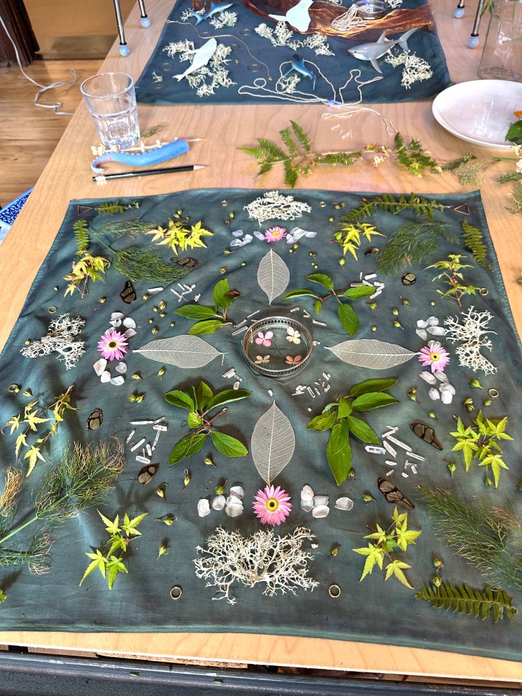 A blue cotton scarf with flowers, leaves, and lichens on top arranged in a pattern