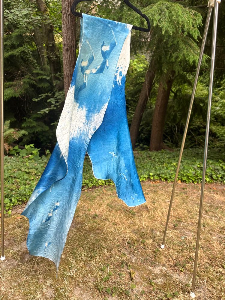 A long blue and white silk scarf with a fluttering rippled shape, cyanotype printed with photographs of trumpeter swans in flight