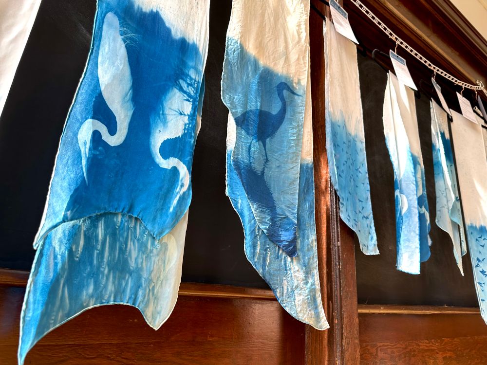 Closeup of the egret silk scarf, depicting a great egret and its reflection on one side and an underwater photograph of a school of fish on the other
