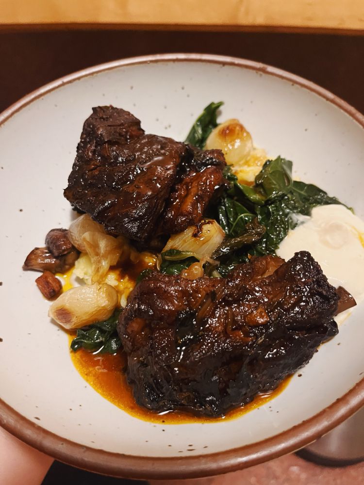 picture of dinner in a white ceramic bowl: red wine braised short ribs; sautéed swiss chard, mushrooms and pearl onions; mashed potatoes; horseradish cream and au jus 