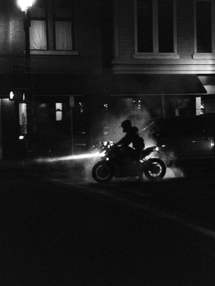 Black and white film photo of a motorcyclist in silhouette, surrounded by the smoke of his burnout being illuminated by the headlights of other motorcyclists behind him.

Taken in September 2025 by Jacy Eberlein in Edmonton, Alberta. Taken on a Leica M3 with a Jupiter-8 on Foma 400.