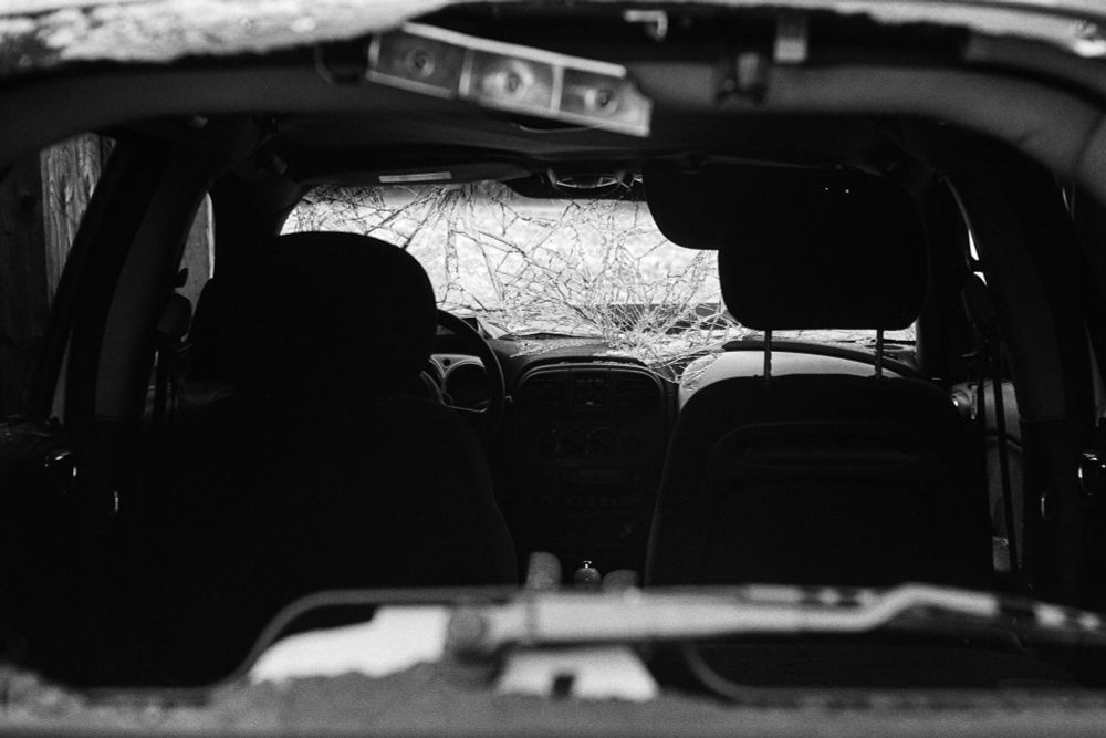 Black and white film photo of the inside of a car, through the broken glass window. The front window has been caved in.

Photo taken November 2025 in Edmonton, Alberta by Jacy Eberlein. Taken on a Leica M3 with a Jupiter-8 on Ilford FP4+.