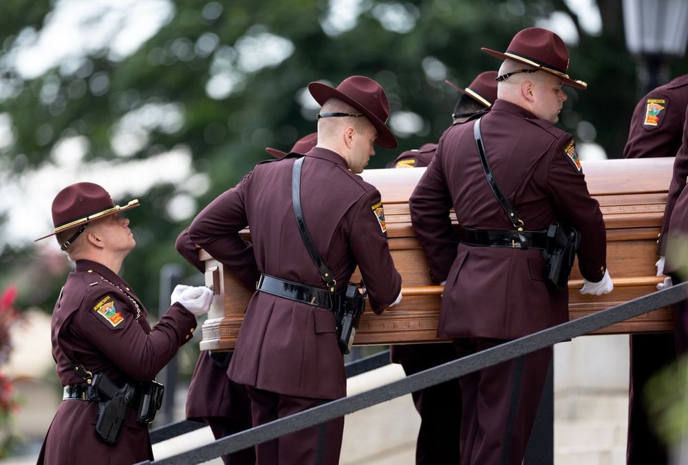 Officers carry the casket of Mark Hortman up the stairs.