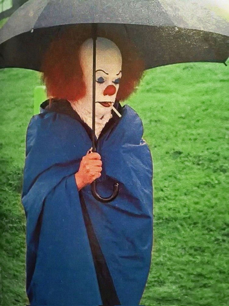 Tim Curry holds umbrella and smokes cigarette on the set of IT