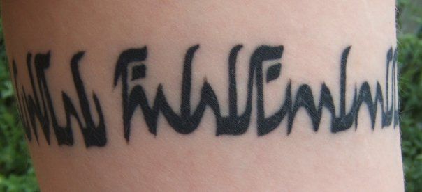 An armband tattoo, whose visible portion reads:
rihl dolgelen