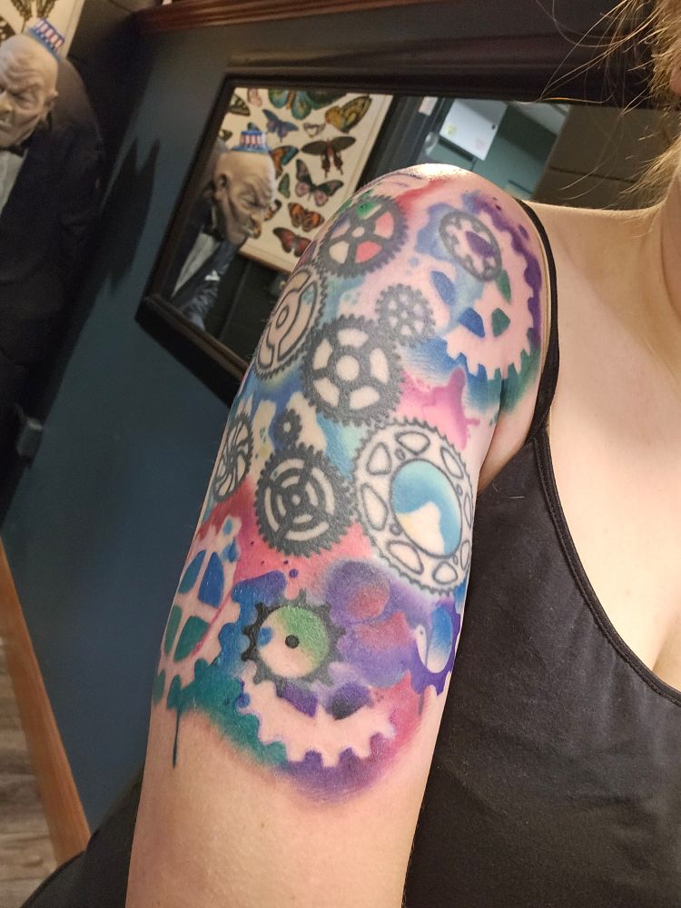 Same tattoo as before, with cogs, but way more colorful now, including colors with clear space in the outline of not cogs/gears
