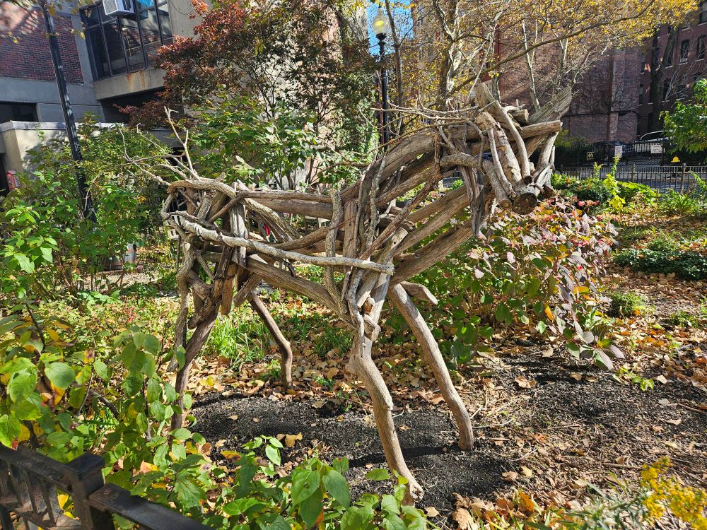 A statue of, I think, a horse, made out of branches, in a tiny garden area