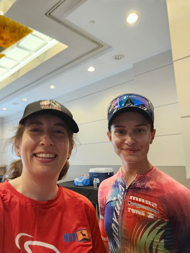 Me, white woman in a red shirt and black hat) and Agnieszka Skalniak-Sójka, younger white woman in a Canyon-SRAM jersey and black baseball hat. 