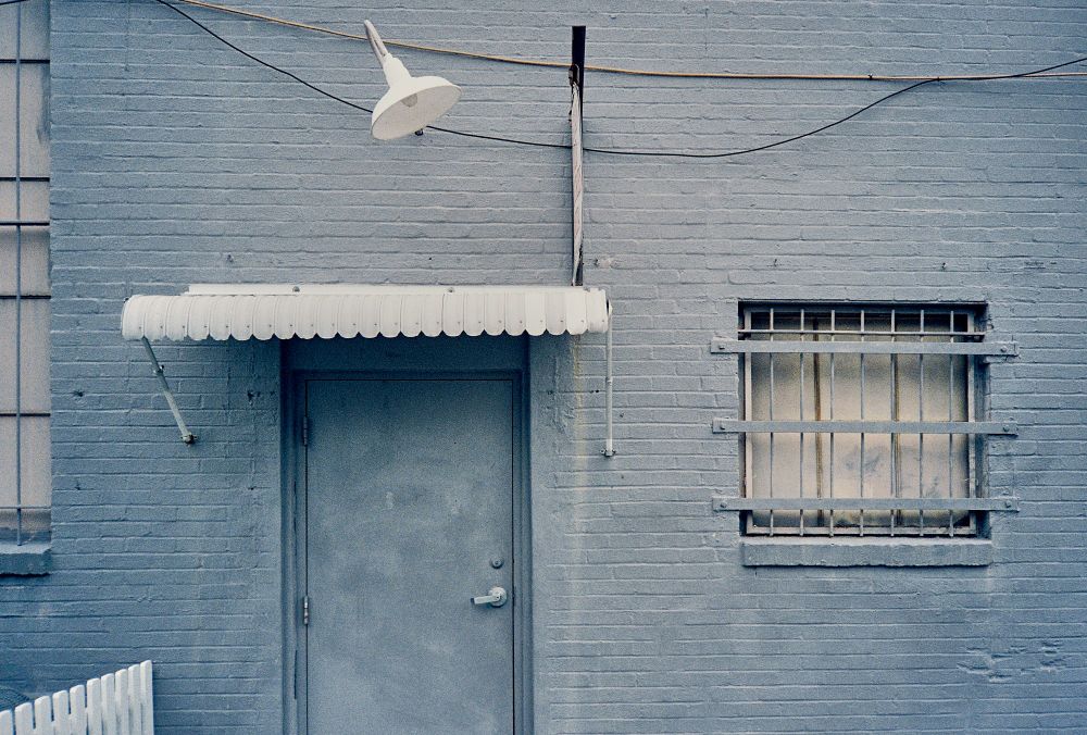 Distressed gray painted building with white accents.