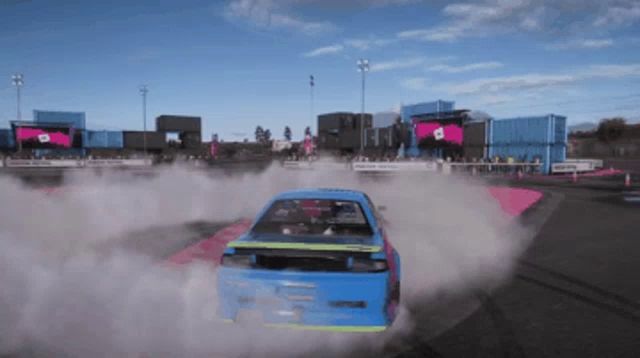 a blue car is driving on a track with smoke coming out of it